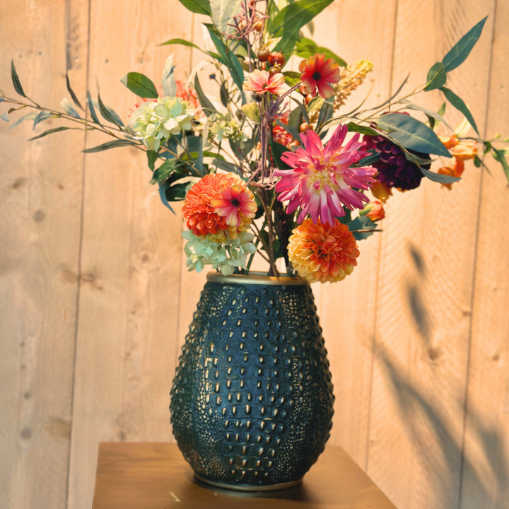 Close-up van het zijdenbloemenboeket Ime van BloomFever met gedetailleerde bloemen in roze, rood, oranje en groene tinten, gestyled in een elegante groene crocodile vaas van PeriLiving.