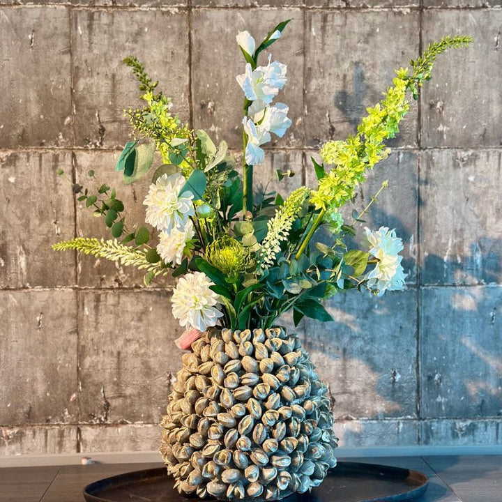 Een elegant kunstbloemenboeket genaamd "Bess", met prachtige witte bloemen in een beige Pistache L vaas van PeriLiving