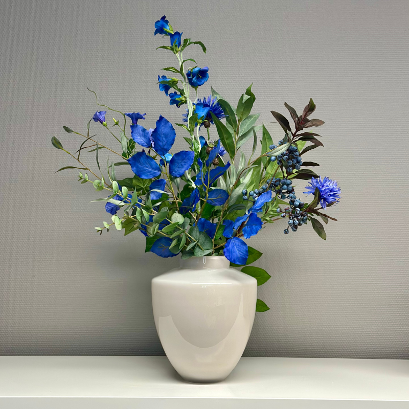 Vaas Tugela Ivory S met exotisch boeket Noëlla, een stijlvolle combinatie van blauwe bloemen en een elegante designvaas voor luxe interieurdecoratie.