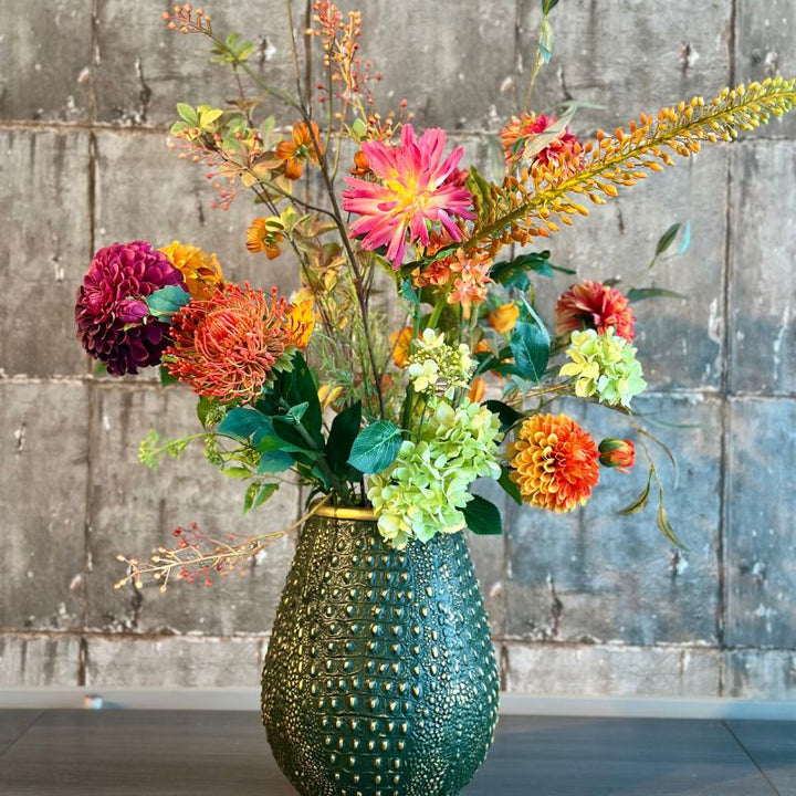 zijdenbloemenboeket Ime van BloomFever met gedetailleerde bloemen in roze, rood, oranje en groene tinten, gestyled in een elegante groene crocodile vaas van PeriLiving.