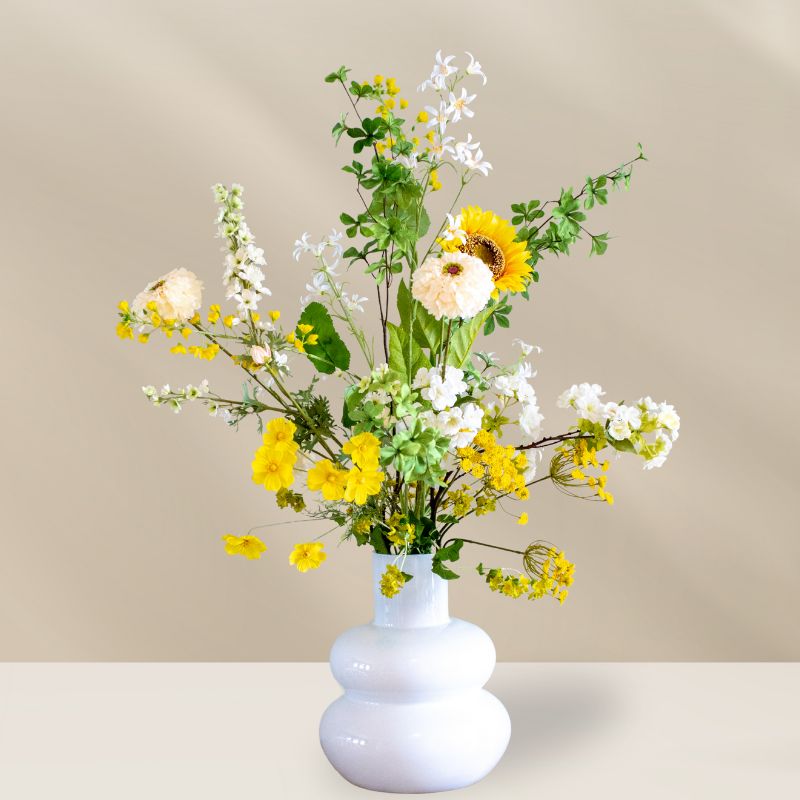 Kunstboeket Aaf met zijden bloemen in de kleuren wit, geel en groen. Bestaat uit o.a. kunst zonnenbloem, witte dahlia,
Gele Gypsohilia's, 
Witte Jasmijntjes