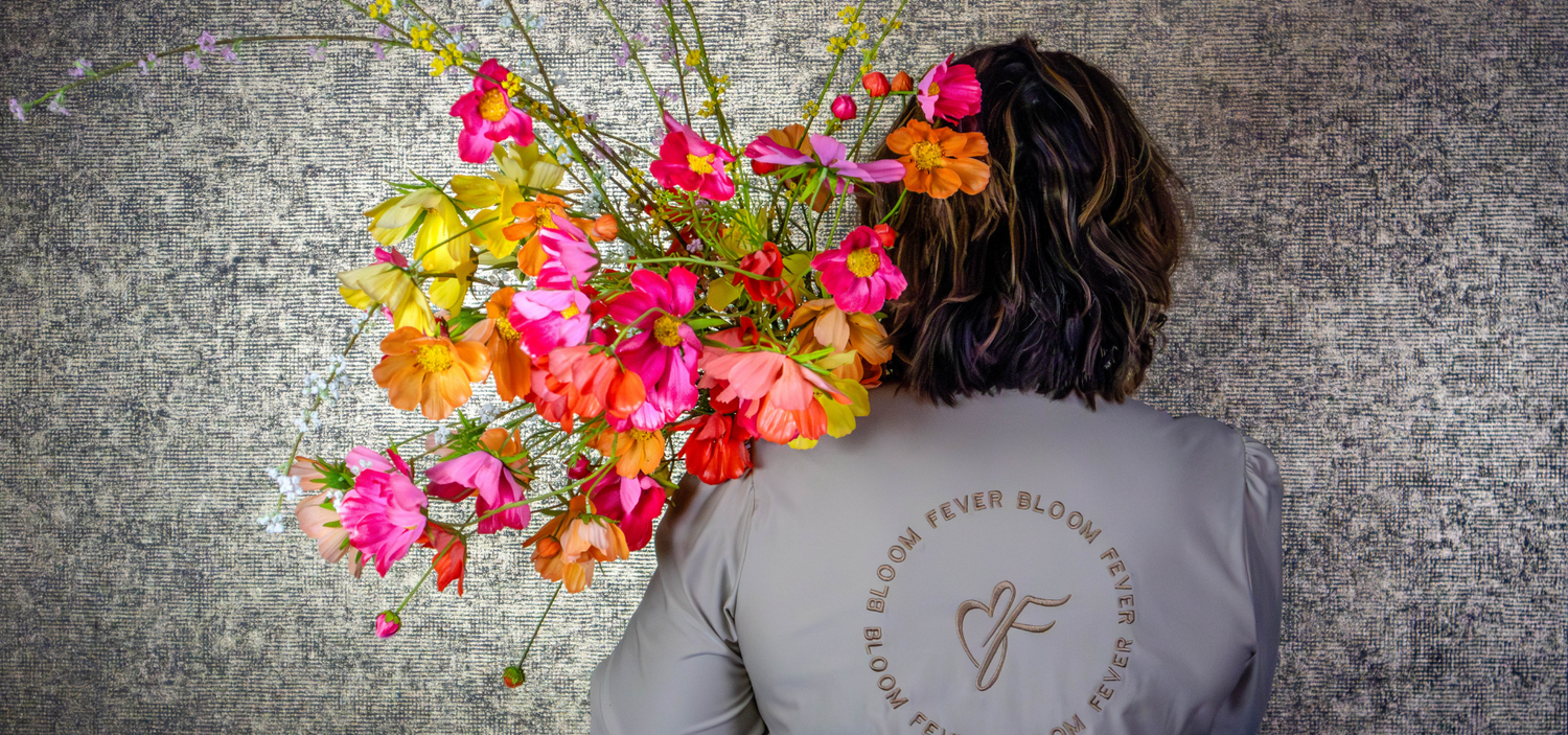 zijden cosmosbloemen in de kleuren geel, oranje, fuchsia en rood. Gepresenteerd als zijden boeket met bedrijfskleding van BloomFever 