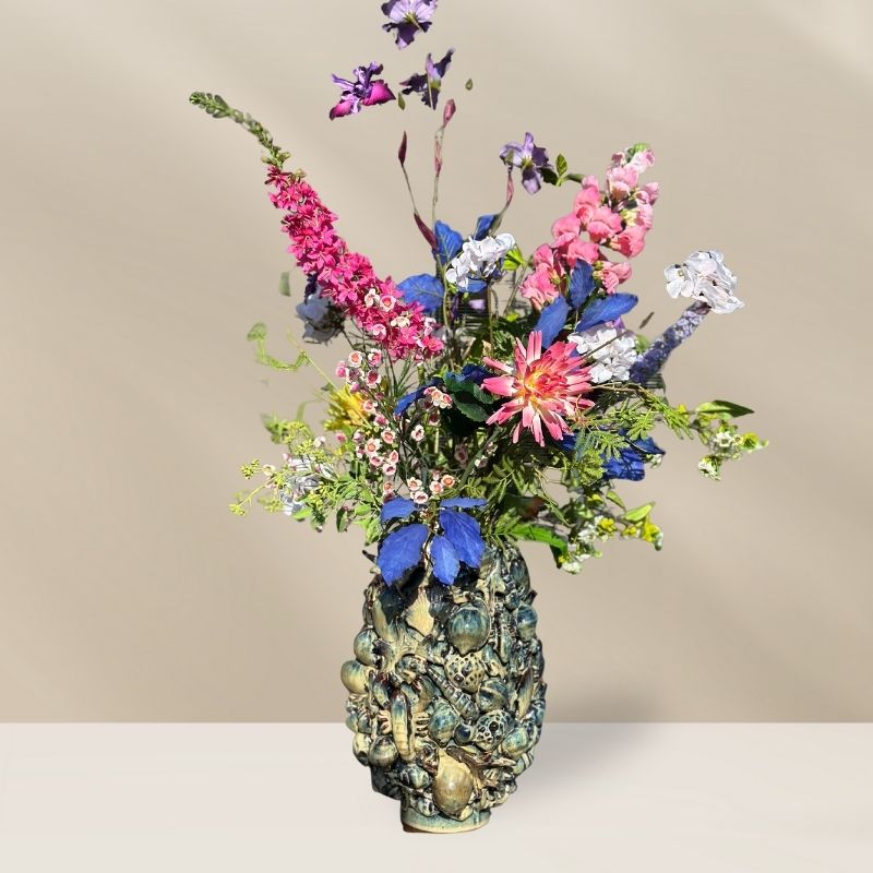 Weelderig kunstboeket Isla met 12 zijden bloemen in diverse heldere kleuren. Gestyled in de prachtige ocean vaas van PeriLiving. Alles verkrijgbaar bij BloomFever