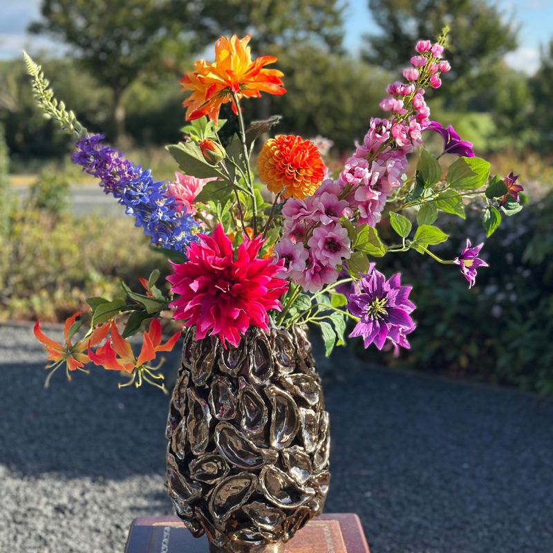 zijden bloemen in diverse kleuren gestyled in een bronzen oystervaas van periliving. Verkrijgbaar bij bloomfever